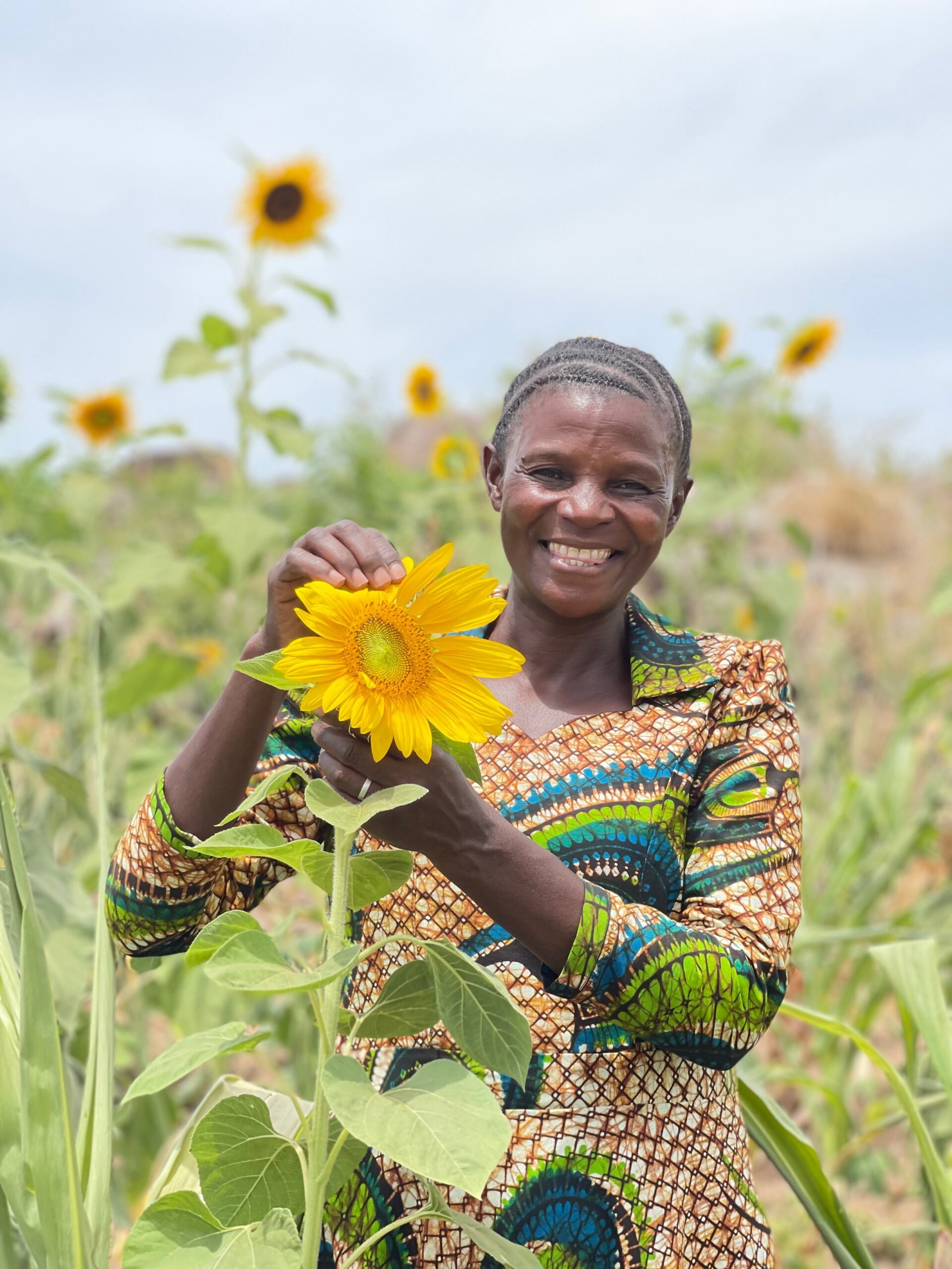 Bild på en kvinna som håller i en solros på ett fält i Tanzania.