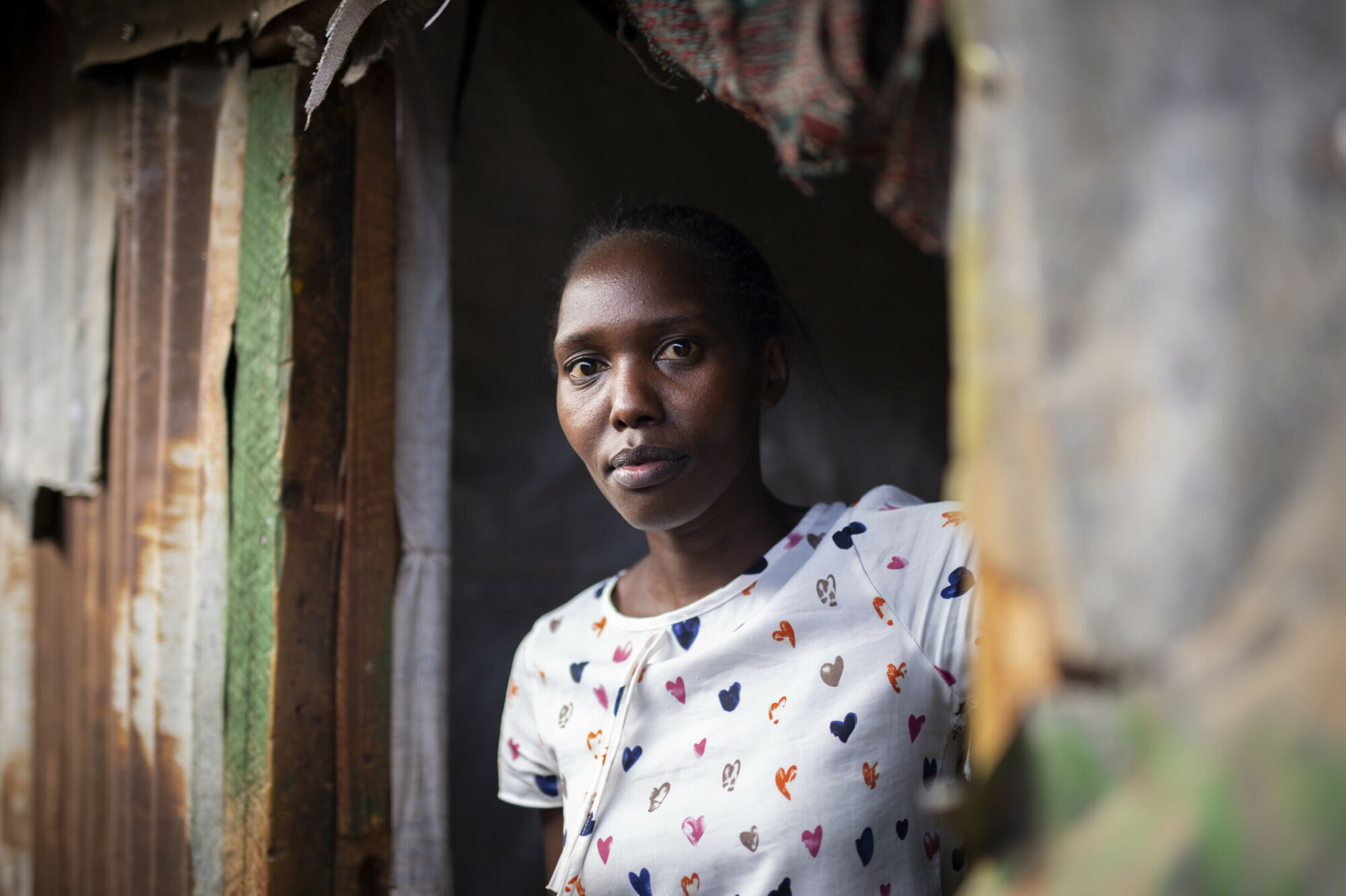 Ung kvinna kikar ut från sitt hem i slumområdet Mathare i Kenya.